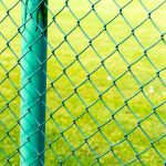 Closeup of chain-link fences in a field under the sunlight with a blurry background