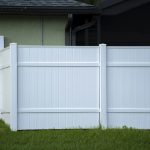 White vinyl picket fence on green lawn surrounding property grounds